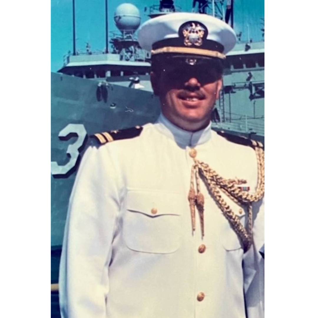 Steve Dahlquist smiling in uniform in front of a boat
